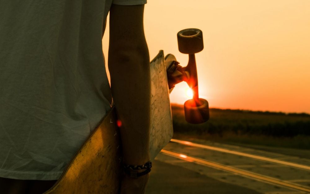 Man with a NHS skateboard in hand admiring the sunset